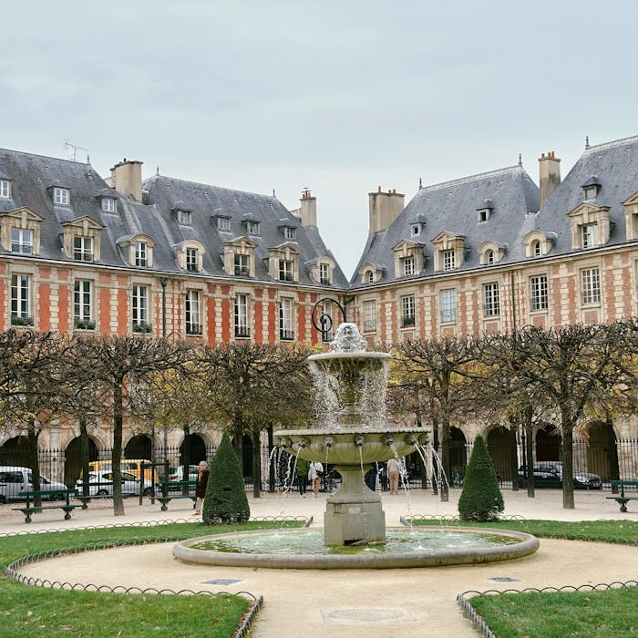 Elegant autumn scene at Place des Vosges in Paris with beautiful fountain and historic architecture.